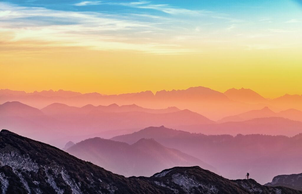 A man captures a breathtaking sunset landscape atop a mountain with photography.