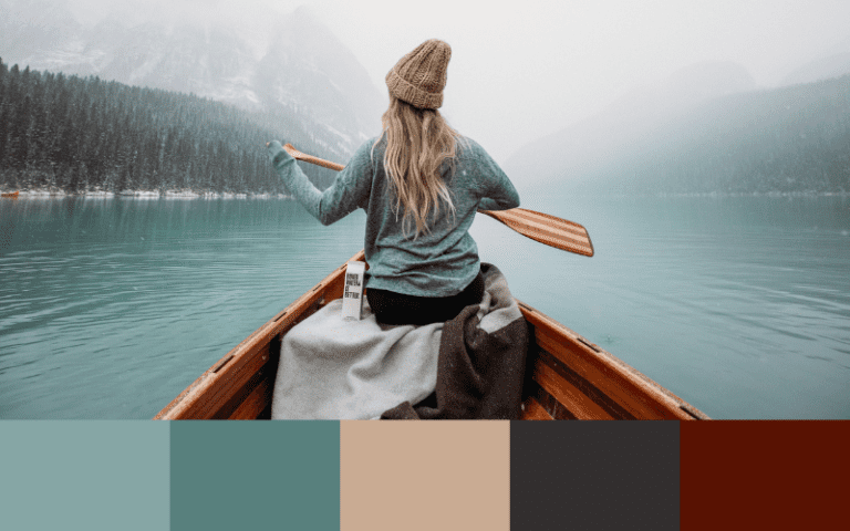 A woman is paddling in a canoe on a serene lake, captured against an exquisite color palette.