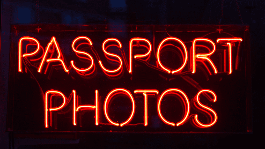 A neon sign that says passport photos.