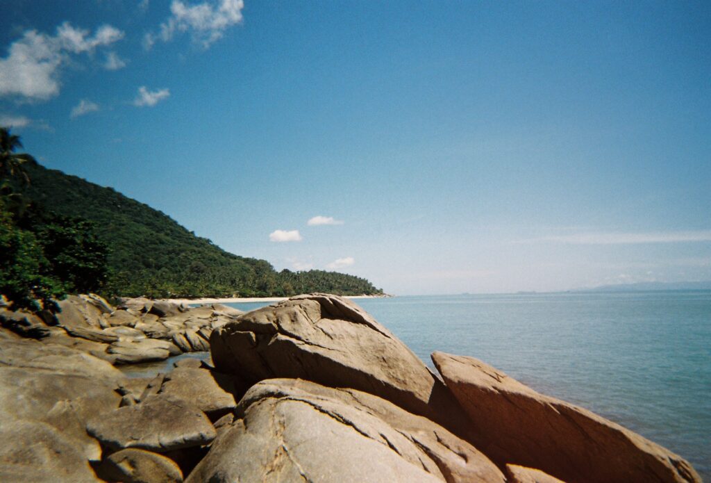 A person is sitting on a rock in the water, captured with exquisite detail using Cinestill 400d.