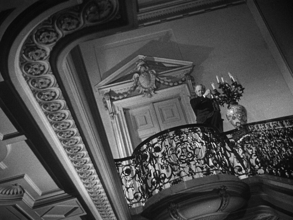 A man on a stairway in an ornate building captured in a Dutch angle shot.