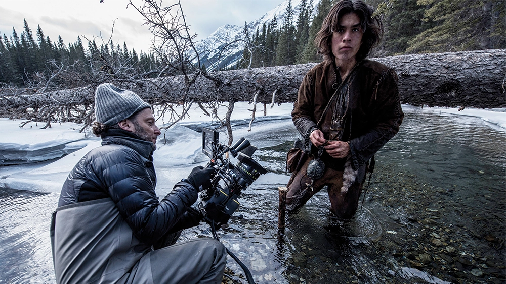 A man is capturing visuals in a river with a camera, showcasing the role of a cinematographer.