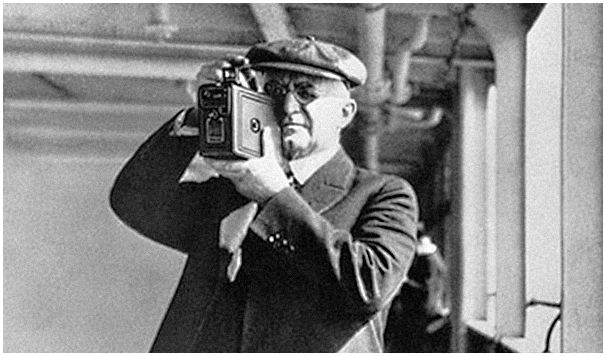 An old photograph of a man holding a camera from the time when the camera was invented.