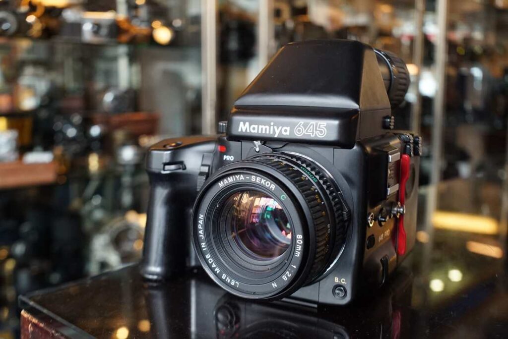A black Mamiya 645 Pro camera sits on a table in a store.
