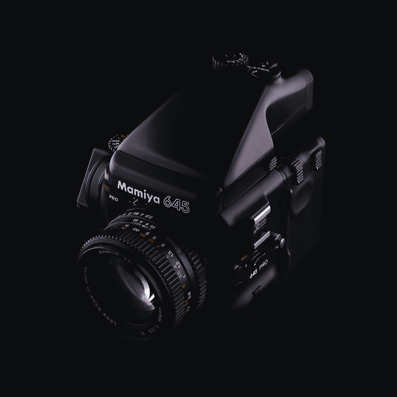 A Mamiya 645 Pro camera on a black background.