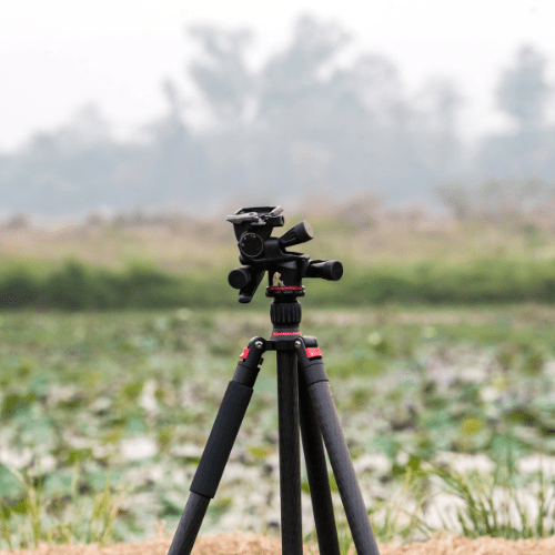 A tripod with a camera in front of a scenic lake.