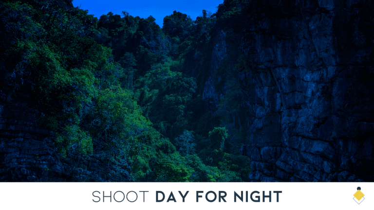 A dark, wooded valley between steep, rocky cliffs, illuminated by a soft, blue light to simulate a nighttime appearance.