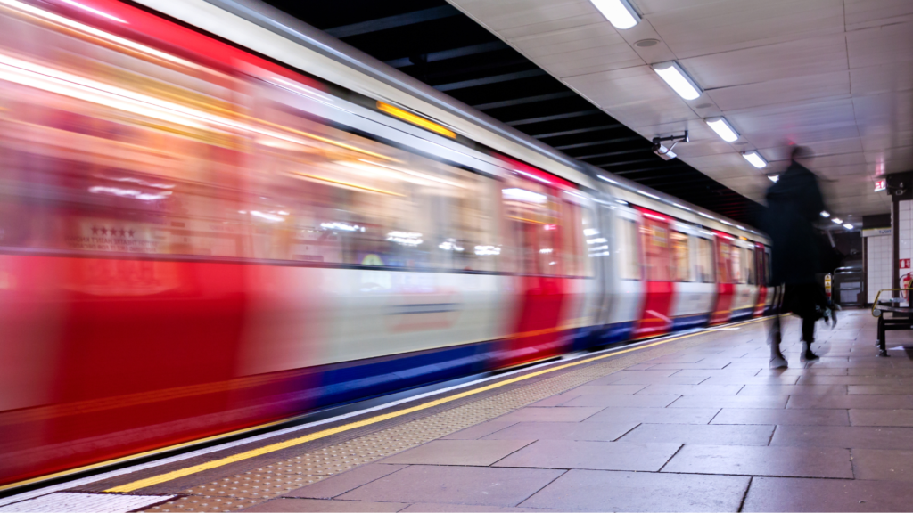 A blurred motion shot, demonstrating mastery over the Photography Exposure Triangle, of a moving train at an underground station with a solitary person waiting on the platform.