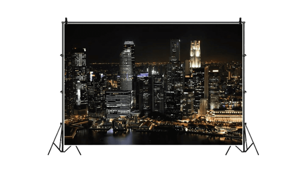 Backdrop of a nighttime cityscape on a stand, showcasing illuminated skyscrapers and reflections on a body of water, ideal as a headshot background.