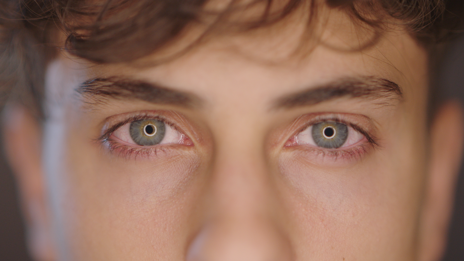 Close-up of a person's eyes with light-colored irises, slightly red around the edges.