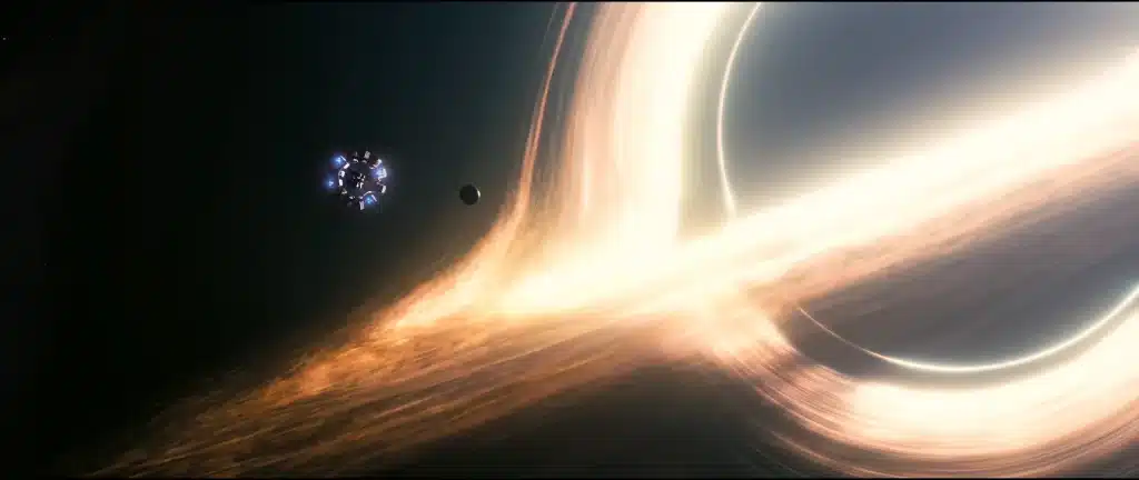 A CGI-rendered spacecraft approaches a bright, swirling black hole in space, accompanied by a nearby planet.