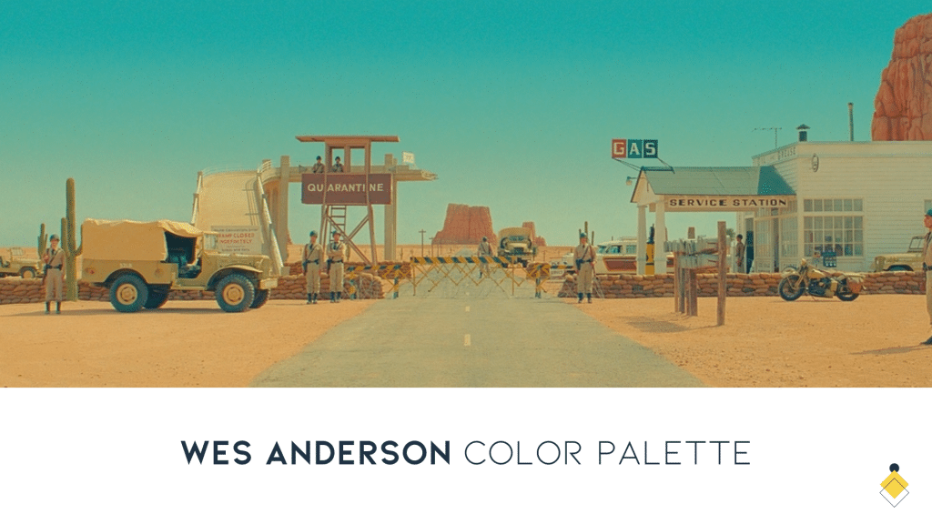 A desert scene features a service station, quarantine checkpoint, and gas pumps. Vehicles and people in light attire add to the tableau. The atmosphere resonates with a distinctive Wes Anderson color palette, infusing the setting with whimsy and charm.