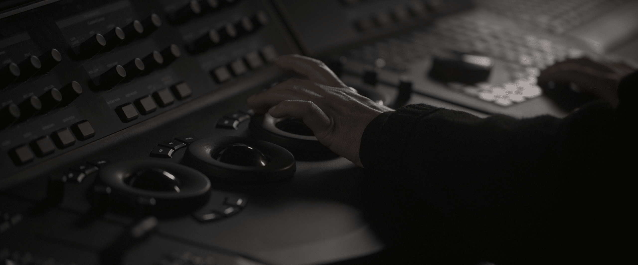 A person operates a control panel with hands adjusting round dials and pressing buttons.