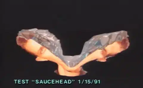 Distorted 3D CGI animation of a face with reflective surfaces, split and mirrored, labeled "TEST 'SAUCEHEAD' 1/15/91" at the bottom.