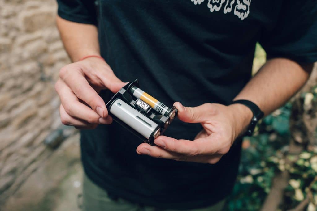 A person holds the open back of a Mamiya 645 film camera, revealing its intricate loading mechanism beneath the open sky.